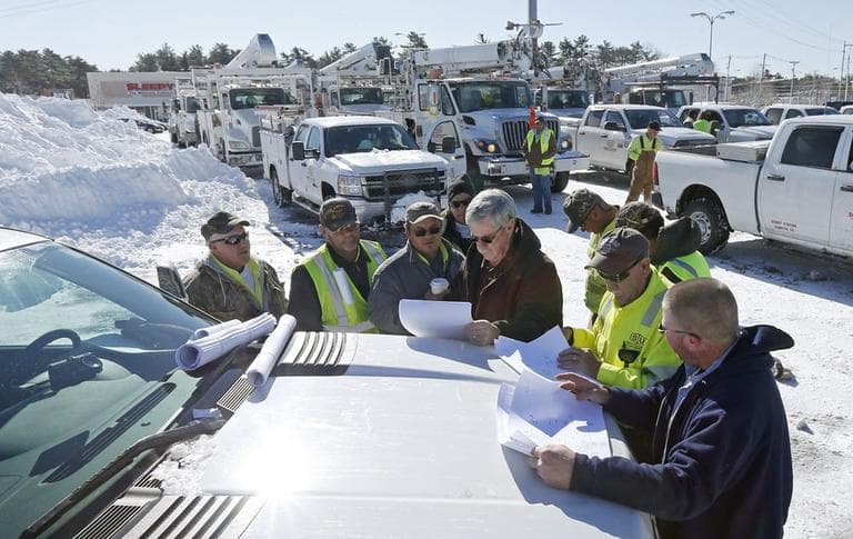 With more than a hundred trucks waiting to deploy, National Grid and utility workers from South Carolina meet on the hood of a pick-up truck to discuss their plan to re-energize towns without power at the Hanover Mall in Hanover, Mass., Sunday, Feb. 10, 2013. (Charles Krupa/AP)