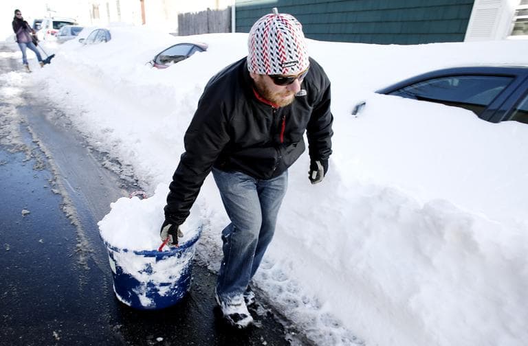 Keith Tobin hauls snow down the street while shoveling out his car in Boston Sunday, Feb. 10, 2013. (Winslow Townson/AP)