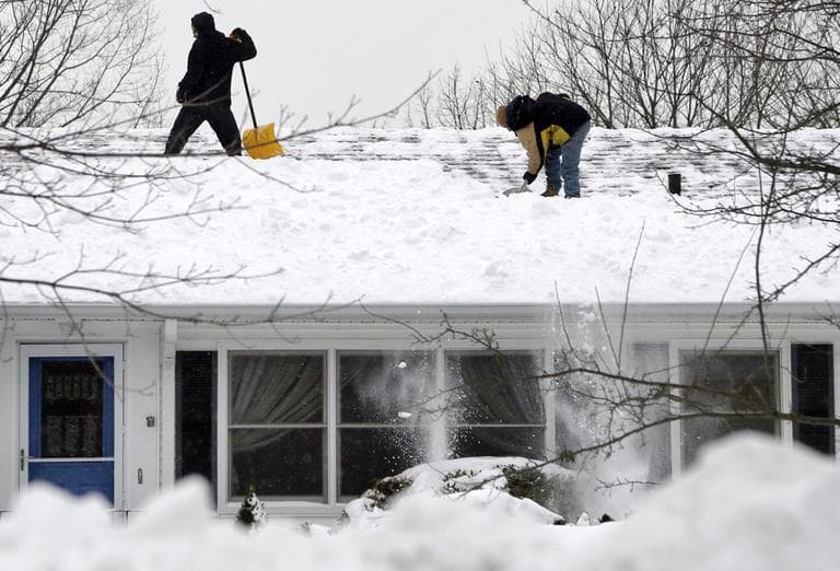 Two men clear snow off a roof of a home in North Andover, Mass. Monday, Feb. 11, 2013. (Elise Amendola/AP)