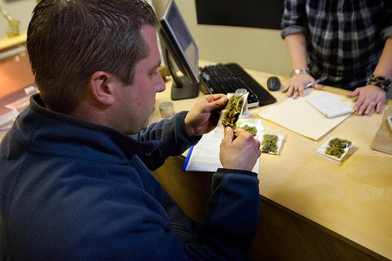 Josh Goulette examines packages of different types of marijuana before purchasing at  Canuvo medical marijuana dispensary in Biddeford, Maine. (Jesse Costa/WBUR)