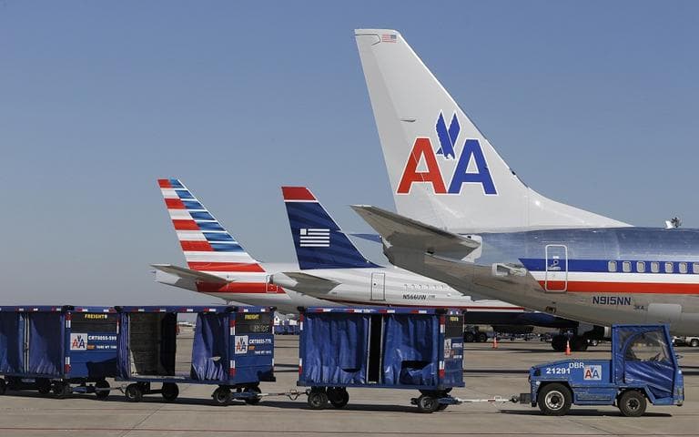 U.S. Airways and American Airlines planes are shown at gates at DFW International Airport. The two airlines will merge forming the world's largest airlines. (LM Otero/AP)