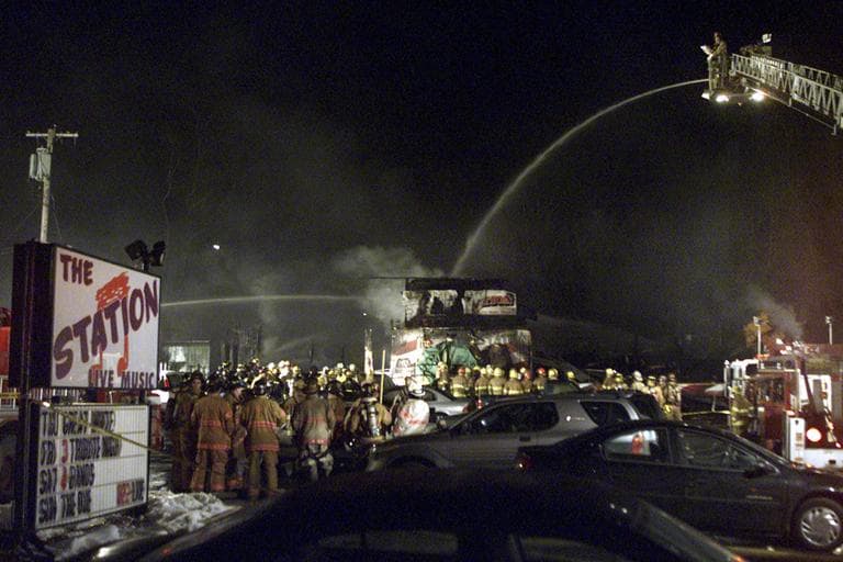 In this Feb. 21, 2003 file photo, firefighters spray water on the charred nightclub, The Station, the morning after a fire engulfed the building, killing 100 people and injuring 200 more. (Stew Milne/AP, File)