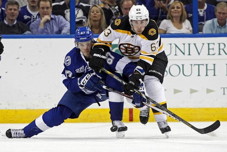 Tampa Bay Lightning's Benoit Pouliot, left, and Boston Bruins' Brad Marchand battle for a puck during the third period. (AP/Mike Carlson)