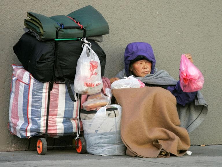 A woman huddles on a street corner in San Francisco in January 2009. (Marcio Jose Sanchez/AP)