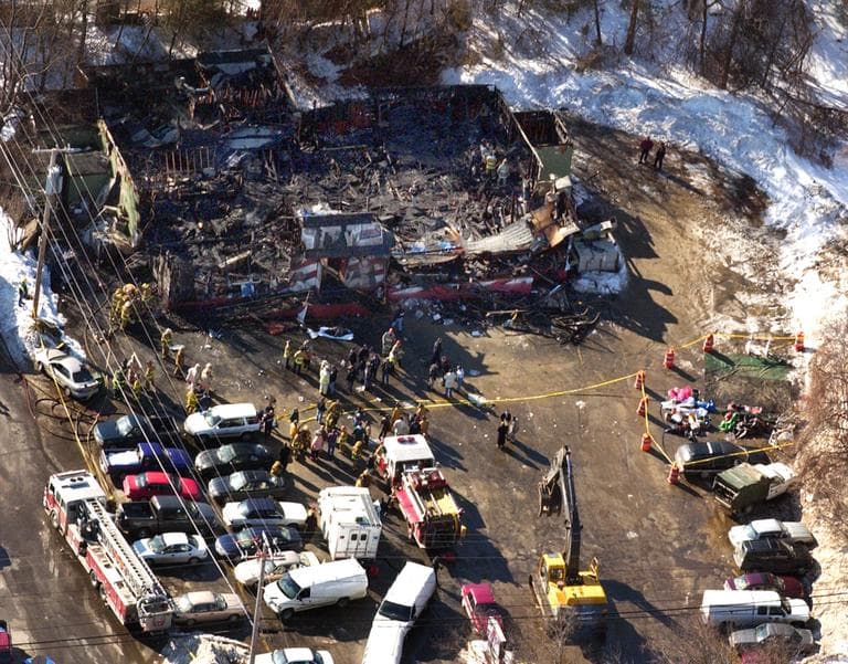 From the air the burned out remains of the Station nightclub where over 59 people died in a late night fire on Thursday, Feb. 20, 2003 in West Warwick, R.I., is seen in the center top, Friday, Feb. 21, 2003. Fire apparatus  and other emergency vehicles were still on the scene along with construction equipment to begin to remove the debris.. (AP Photo/ Robert E. Klein)