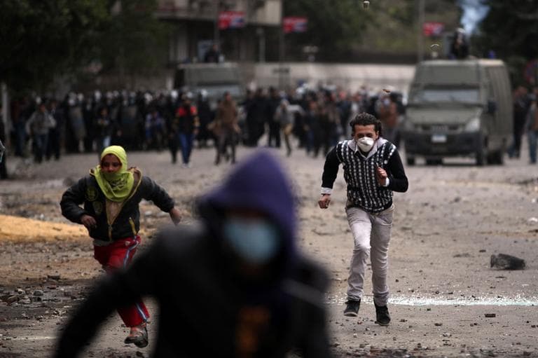 Egyptian protesters run for cover during clashes with riot police near Tahrir Square, Cairo, Egypt.  (AP)