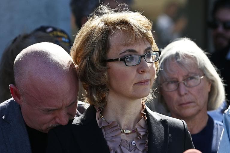 Former Rep. Gabrielle Giffords, center, is joined by her husband on Wednesday at the site of a shooting that left her critically wounded. (Ross D. Franklin/AP)