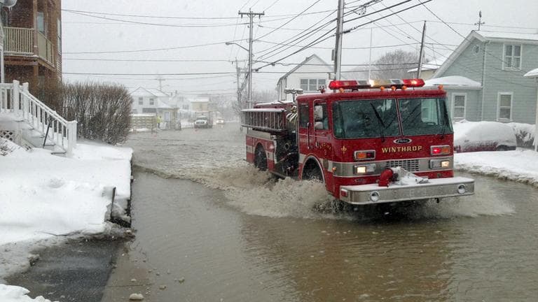 A firetruck drives down a flooded street on Shirley Point in Winthrop Friday morning. (Jesse Costa/WBUR)