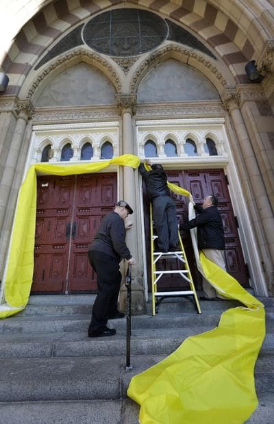 Volunteers hang papal bunting to signify the naming of a new pope, outside Cathedral of the Holy Cross, in Boston on Wednesday. (Steven Senne/AP)