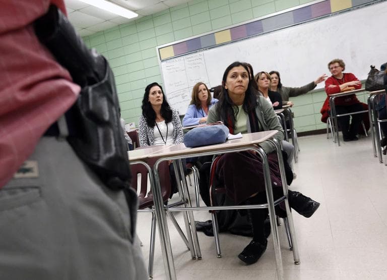 Teacher Astrid Barrios, center, listens as Milford, Mass., police detective Carlos Sousa, left, debriefs participants after a lockdown exercise at Milford High School Milford, Friday, March 15, 2013. (Michael Dwyer/AP)