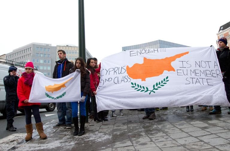 People hold a banner with the flag of Cyprus on it during a demonstration outside of an emergency eurogroup meeting in Brussels on Sunday, March 24, 2013. (Virginia Mayo/AP)