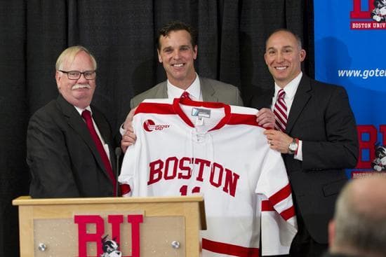 President Robert A. Brown (left) and Mike Lynch, assistant VP and director of athletics, present a jersey to newly appointed men's hockey head coach David Quinn. Quinn comes back to BU from the Colorado Avalanche, where he has been an assistant coach. (Cydney Scott/BU)