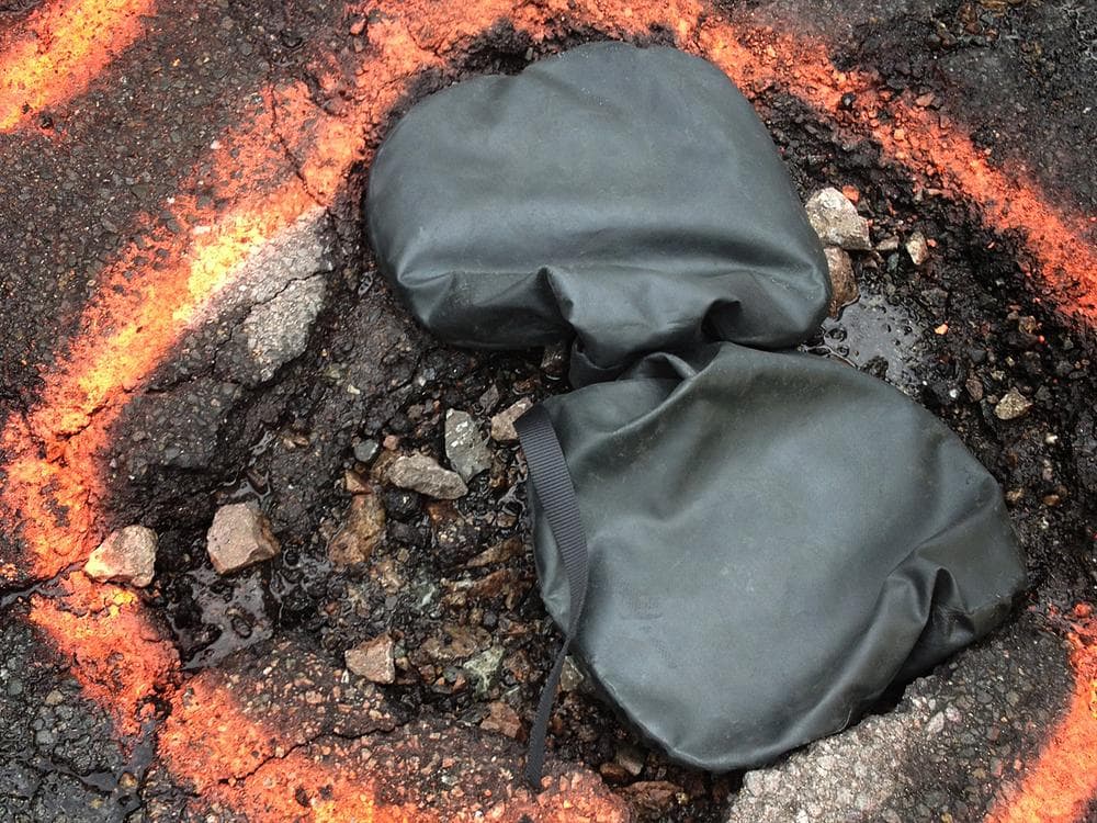One new method is a temporary one: a bag filled with Silly-Putty-like material is placed over a pothole to protects cars until it can be permanently filled. (Asma Khalid/WBUR)