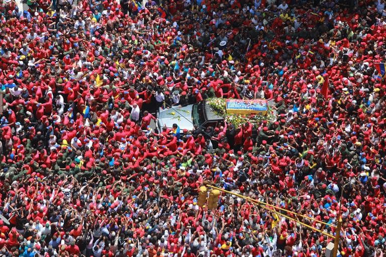 In this photo released by Miraflores Press Office, people surround the flag-draped coffin carrying the body of Venezuela's late President Hugo Chavez as his supporters crowd the streets during the procession from the hospital where he died on Tuesday to a military academy where his body will lie in state in Caracas, Venezuela, Wednesday, March 6, 2013. (AP)