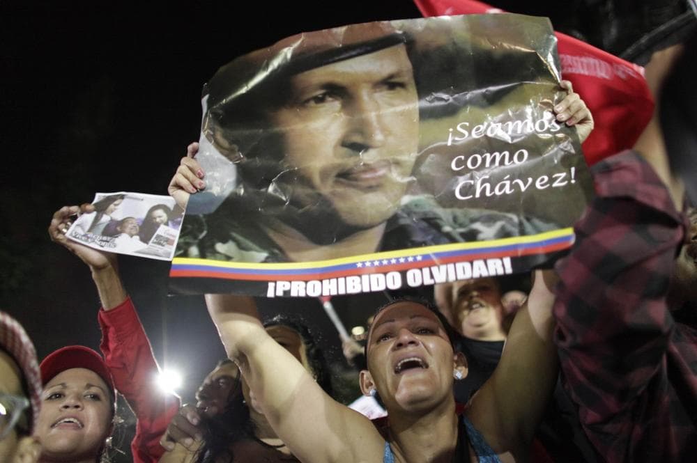 A supporter of Venezuela's late President Hugo Chavez cries as she holds up a poster of Chavez that reads in Spanish &quot;Let's be like Chavez&quot; and &quot;Forbidden to forget&quot; as Chavistas gather in Bolivar square to mourn Chavez's death in Caracas, Venezuela, Tuesday, March 5, 2013. (AP)