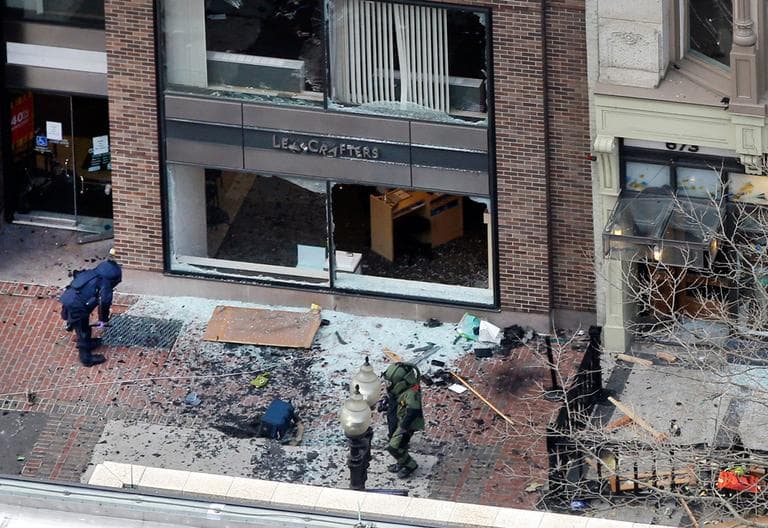 One of the two blast sites on Boylston Street near the finish line of the 2013 Boston Marathon is investigated by two people in protective suits Monday. (Elise Amendola/AP)