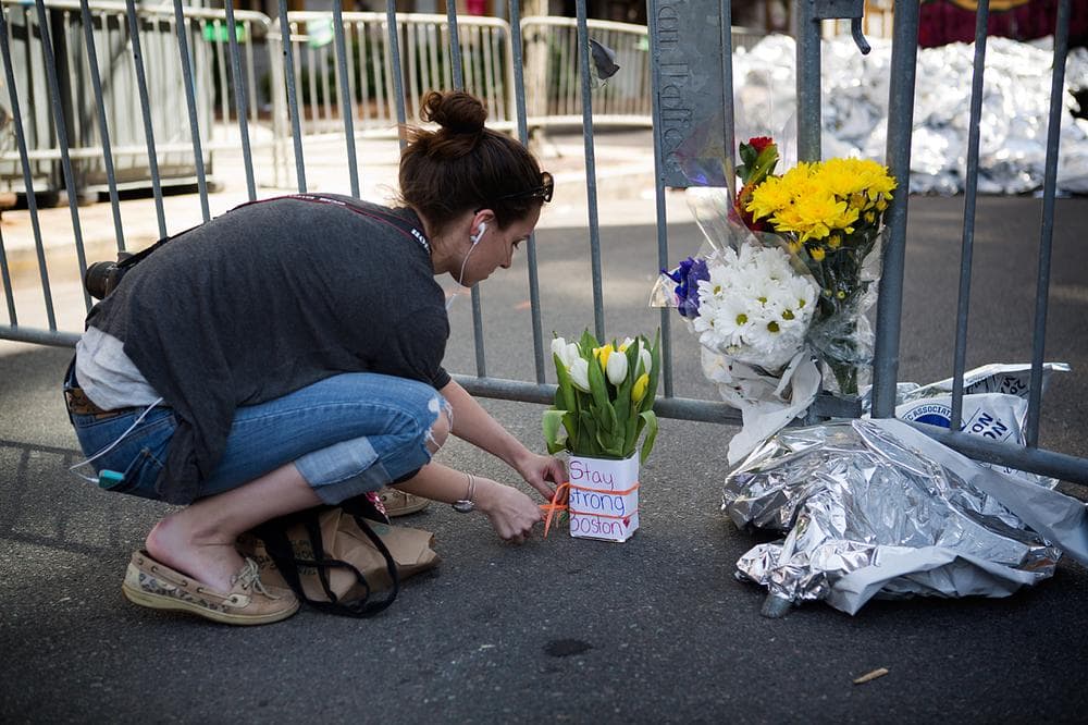 Caitlin Drown of Brewster leaves flowers at a memorial at Dartmouth and Newbury Streets. (Jesse Costa/WBUR)