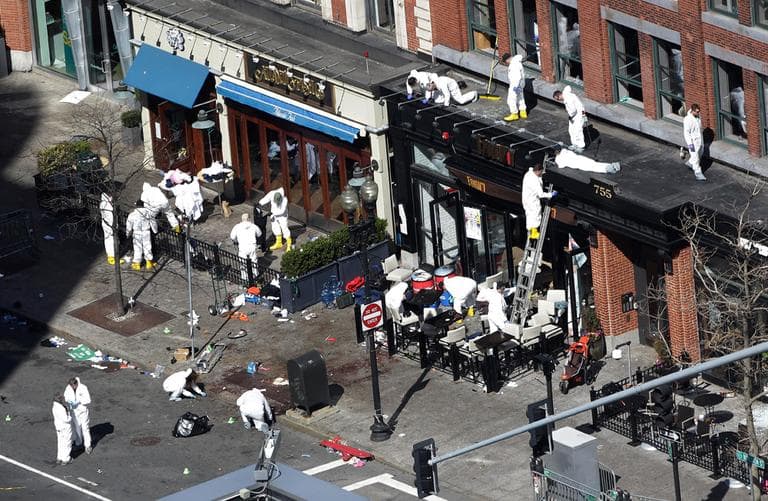 Investigators comb through the scene of one of the blast sites of the Boston Marathon explosions Wednesday. (Julio Cortez/AP)