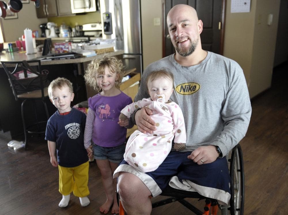 Tom Davis holds his daughter Lylli with two of his other children Isaiah, far left, and Elli looking on in the kitchen of the Davis home Thursday, Feb. 12, 2009, in Fremont, Ind. (AP Photo/Joe Raymond)