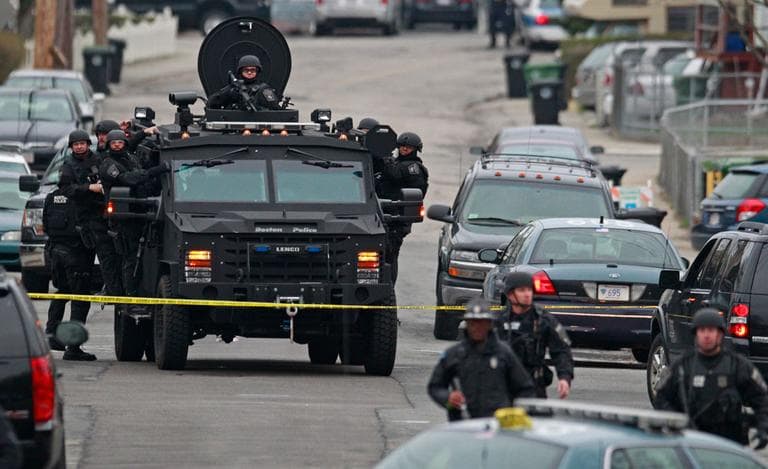 Police in tactical gear arrive on an armored police vehicle as they surround an apartment building while looking for a suspect in the Boston Marathon bombings in Watertown, Mass., Friday, April 19, 2013. (AP Photo/Charles Krupa)
