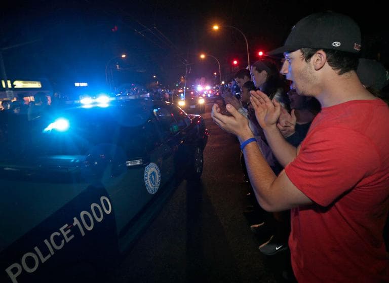 A man applauds as police leave the Watertown scene of the arrest of a suspect of the Boston Marathon bombings Friday night. (Charles Krupa/AP)