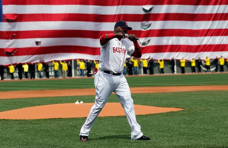 Boston Red Sox's David Ortiz pumps his fist in front of an Amarican flag and a line of Boston Marathon volunteers, background, after addressing the crowd before a baseball game between the Boston Red Sox and the Kansas City Royals in Boston, Saturday, April 20, 2013. (Michael Dwyer/AP)