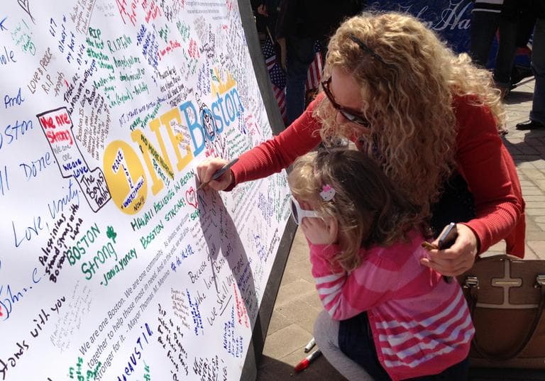 Heidi Barber and daughter Nadia write &quot;Good night to Martin&quot; on the memorial at Boylston Street Wednesday.  (Fred Bever/WBUR)