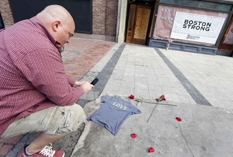 Joe Burke, of Haverhill, places a t-shirt at the spot where the first bomb detonated Wednesday. (Michael Dwyer/AP)