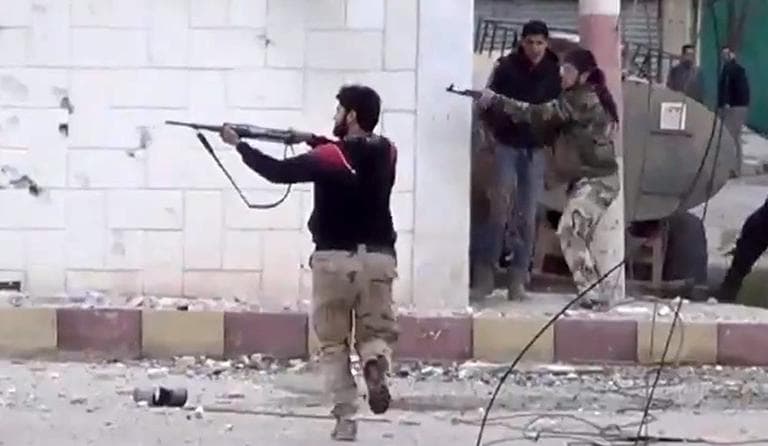 This image taken from video shows free Syrian Army fighters firing at Syrian army soldiers during a fierce firefight in Daraa al-Balad, Syria, March 18, 2013. (Shaam News Network via AP)