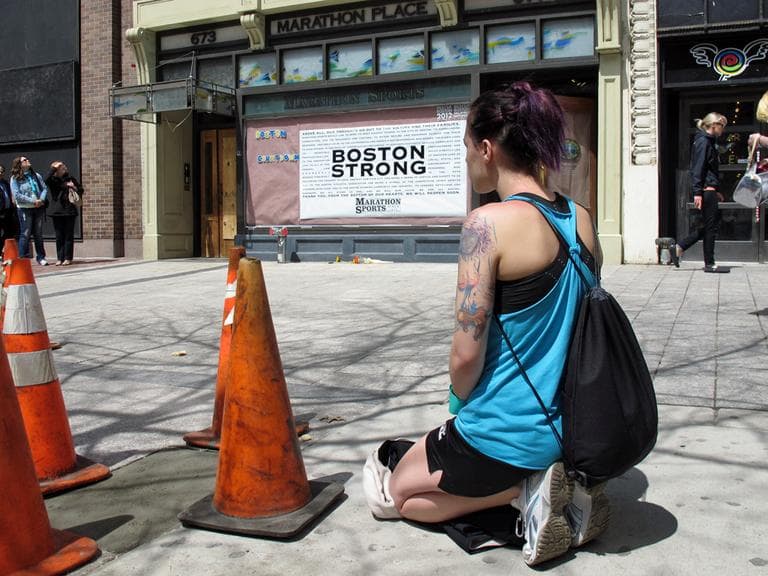 A woman kneels at the site of the first Boston Marathon blast. (Kathleen McNerney/WBUR)