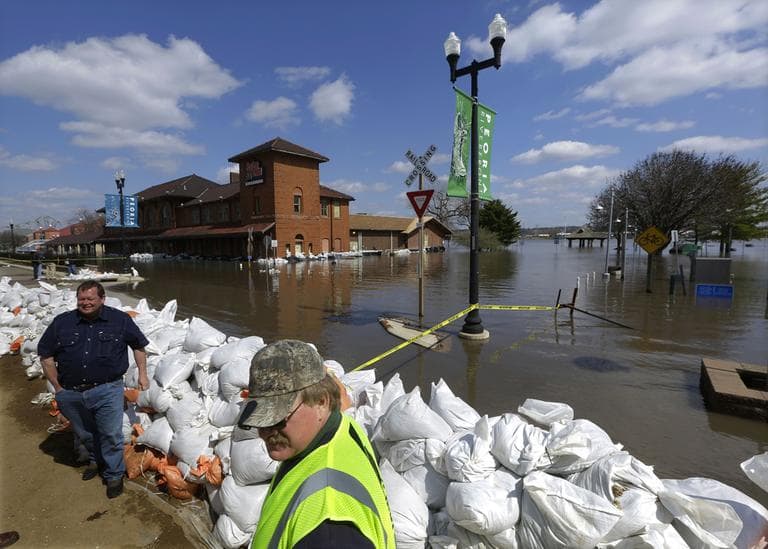 Peoria Maintenance Engineer Jim Clark, right bottom, monitors the sand bag wall holding back the Illinois River from recent flooding Wednesday, April 24, 2013, in Peoria, Ill. The Illinois River finally crested Tuesday at 29.35 feet, eclipsing a 70-year record in Peoria. (Seth Perlman/AP)
