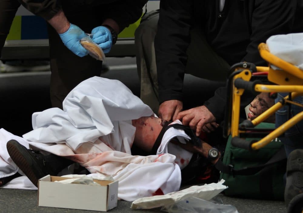 In this Monday, April 15, 2013 file photo, emergency personnel assist a wounded person on the sidewalk after an explosion at the 2013 Boston Marathon in Boston. In a rebuttal to the terrorists and a tribute to stellar medical care, all of the more than 180 people injured in the Boston Marathon blasts one week ago who made it to a hospital alive now seem likely to survive. (AP Photo/Kenshin Okubo, File)