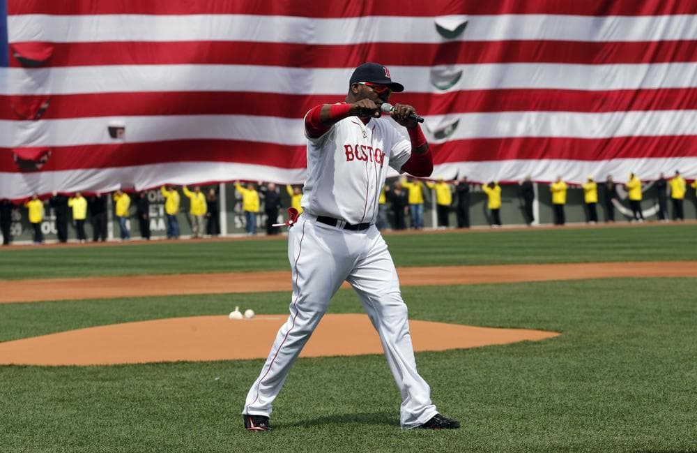 Boston Red Sox's David Ortiz pumps his fist in front of an Amarican flag and a line of Boston Marathon volunteers, background, after addressing the crowd before a baseball game between the Boston Red Sox and the Kansas City Royals in Boston, Saturday, April 20, 2013. (AP Photo/Michael Dwyer)