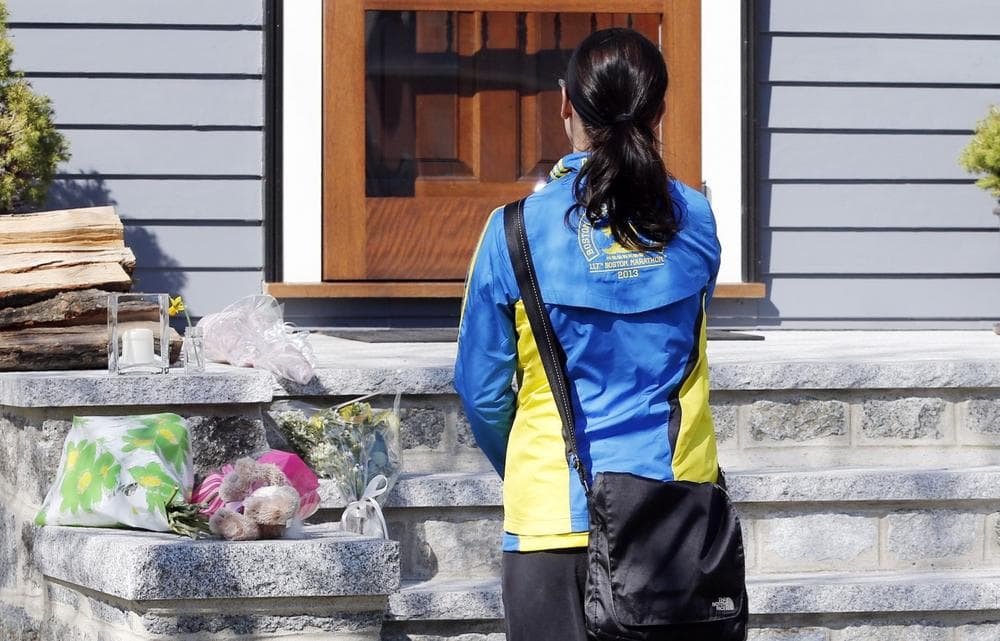 Runner Megan Cloke pauses after placing flowers on the doorstep of the Richard house in the Dorchester neighborhood of Boston,Tuesday, April 16, 2013. Martin Richard,8, was killed in Mondays' bombings at the finish line of the Boston Marathon. The boys mother, Denise, and 6-year-old sister, Jane, were badly injured.  (AP Photo/Michael Dwyer)