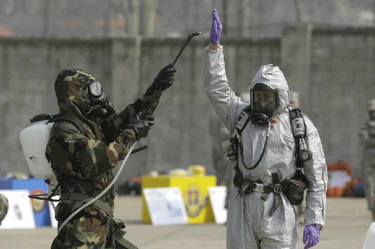 Soldiers of the U.S. Army 23rd chemical battalion, wearing anti-chemical suits check mock chemical pollutants on each other for a demonstration of their equipment during a ceremony to recognize the battalion's official return to the 2nd Infantry Division based in South Korea at Camp Stanley in Uijeongbu, north of Seoul, Thursday, April 4, 2013. (AP)