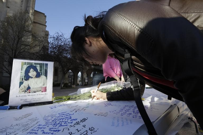 A student writes a message on a makeshift  memorial for Lu Lingzi, one of three fatal victim's from Monday's marathon bombing, outside BU's Marsh Chapel Wednesday. (Julio Cortez/AP)