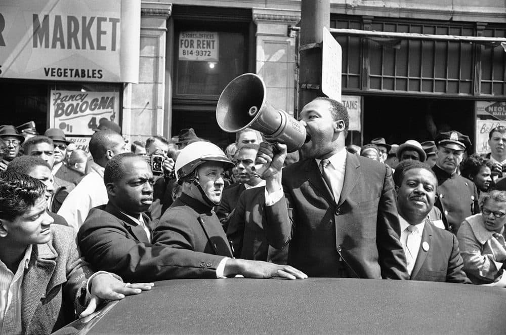 Martin Luther King, Jr. addresses a crowd with a bull horn in Roxbury on April 22, 1965. King was in Boston to lead a civil rights march. (AP)