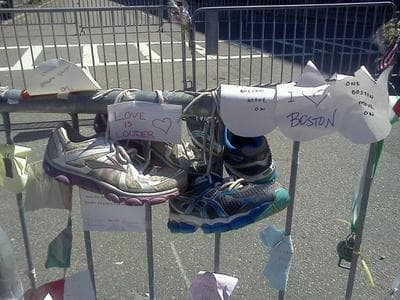 Running shoes are tied to one of the barricades around the Boston Marathon bombing crime scene, in a makeshift memorial to victims. (Karyn Miller-Medzon/Here &amp; Now)