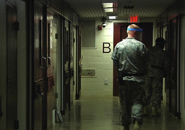 In this April 18, 2013 video frame grab reviewed by the U.S. military, soldiers walk past detainees' cells during early morning prayer at Guantanamo Bay Naval Base, Camp 5, in Cuba. (AP) 