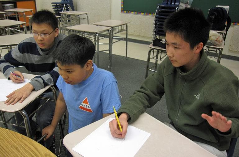 Michael Ren, center, reads a math problem to his teammates James Lin, right, and Alec Sun as they compete to see who can answer first. The three of them, plus Matthew Lipman (not pictured), make up the Massachusetts Mathletes. (Asma Khalid/WBUR)