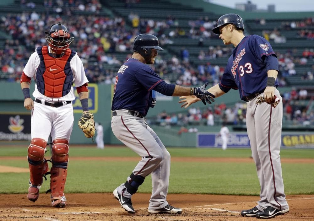 Twins designated hitter Ryan Doumit is greeted at the plate by Justin Morneau after his two-run home run as Boston Red Sox catcher Jarrod Saltalamacchia watches on. (AP)