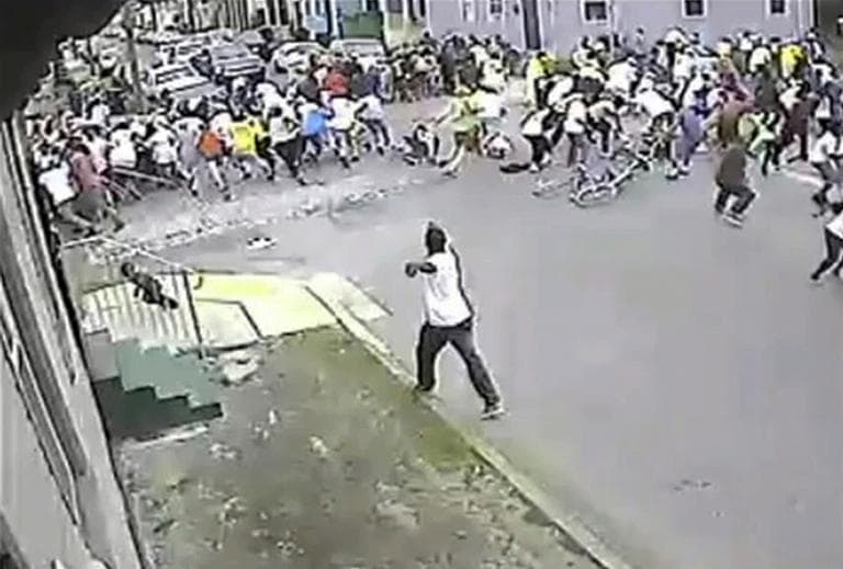 In this image taken from video and provided Monday, May 13, 2013, by the New Orleans Police Department, a possible shooting suspect in a white shirt, bottom center, shoots into a crowd of people, Sunday in New Orleans. (New Orleans Police Department via AP)
