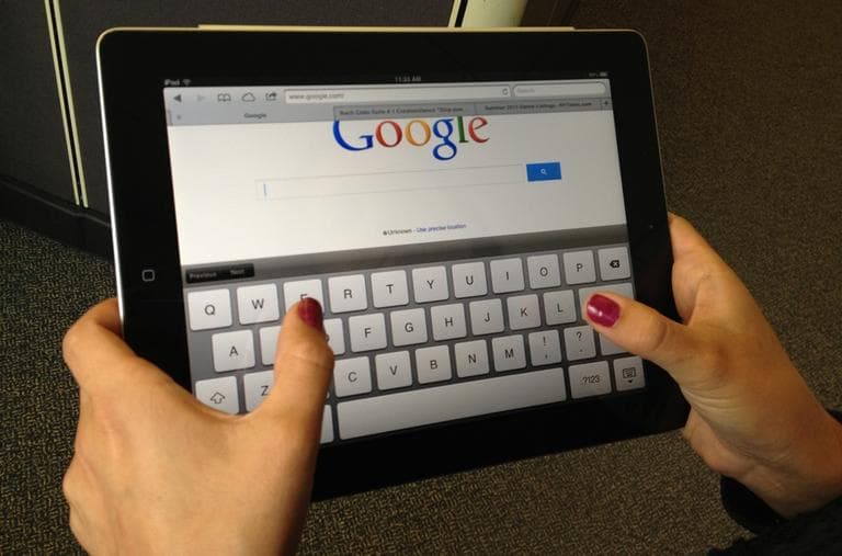An iPad user types on a virtual QWERTY keyboard. (Here &amp; Now)