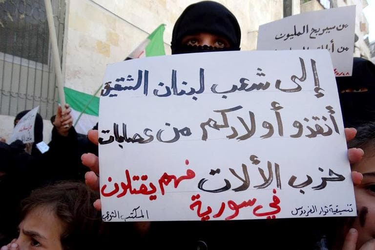 Citizen journalism image provided by Aleppo Media Center, which has been authenticated based on its contents and other AP reporting, an anti-Syrian regime protester holds a poster in Arabic that reads, &quot;to the great Lebanese people save your children from Hezbollah gangs, they kill in Syria,&quot; during a demonstration, in Aleppo, Syria, Tuesday May 28, 2013. (Aleppo Media Center/AP)