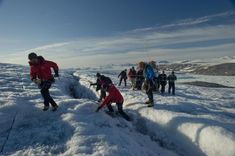 An expedition team of U.S. Coast Guard service members and North South Polar Inc. explorers transports an ice melting machine over a crevasse near Koge Bay, Greenland, in 2012. The team used the machine to melt through the ice to locate the possible crash site of a WWII Coast Guard Grumman Duck. (Courtesy U.S. Coast Guard/Petty Officer 2nd Class Jetta H. Disco)