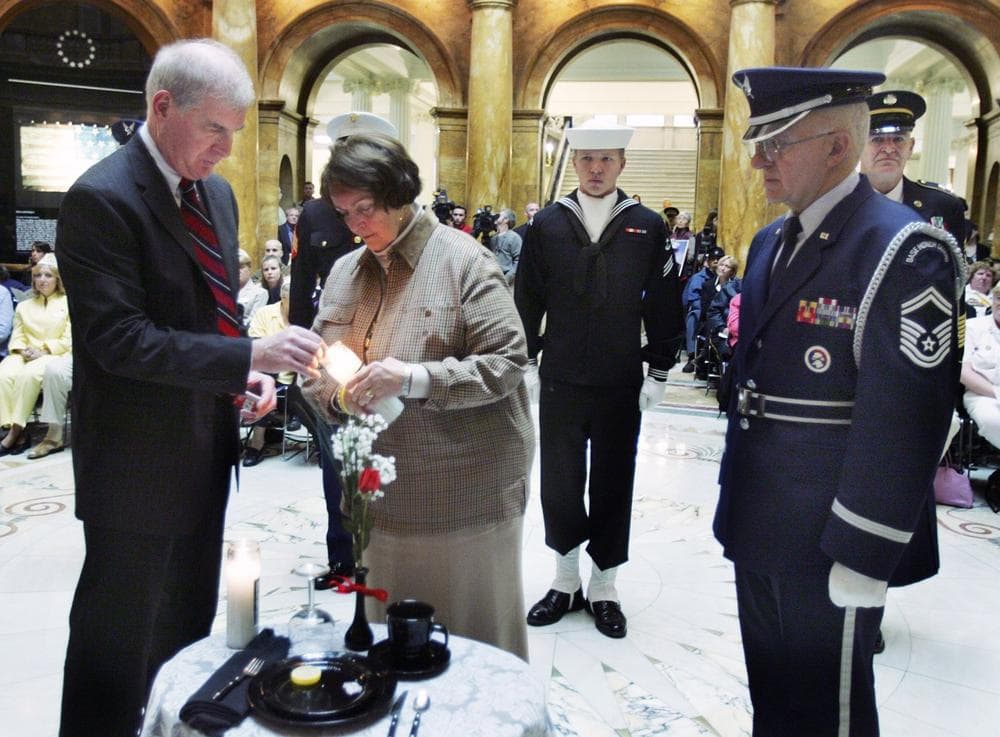 Former prisoner of war Cdr. Timothy Sullivan, left, and Maureen Dunn of the National League of Families POW/MIA, light a candle at a table setting that signifies those soldiers missing in action during Veterans' Day ceremonies in Boston, Friday, Nov. 11, 2005. (Michael Dwyer/AP)