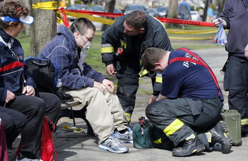 Firefighters tend to a man following an explosion at the finish line of the Boston Marathon in Boston, Monday, April 15, 2013. (AP Photo/Michael Dwyer)