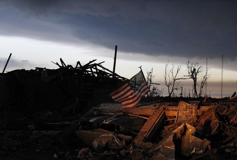 At sunrise, Tuesday May 21, 2013, an American flag blows in the wind atop the rubble of a destroyed home in Moore, Oklahoma. (AP/Brennan Linsley)