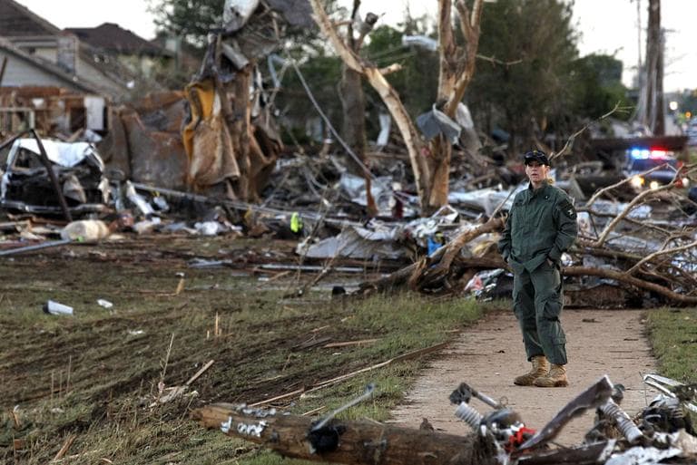A member of a security team helps guard an area of rubble from a destroyed residential neighborhood on Tuesday, one day after a tornado moved through Moore, Okla. (Brennan Linsley/ AP)