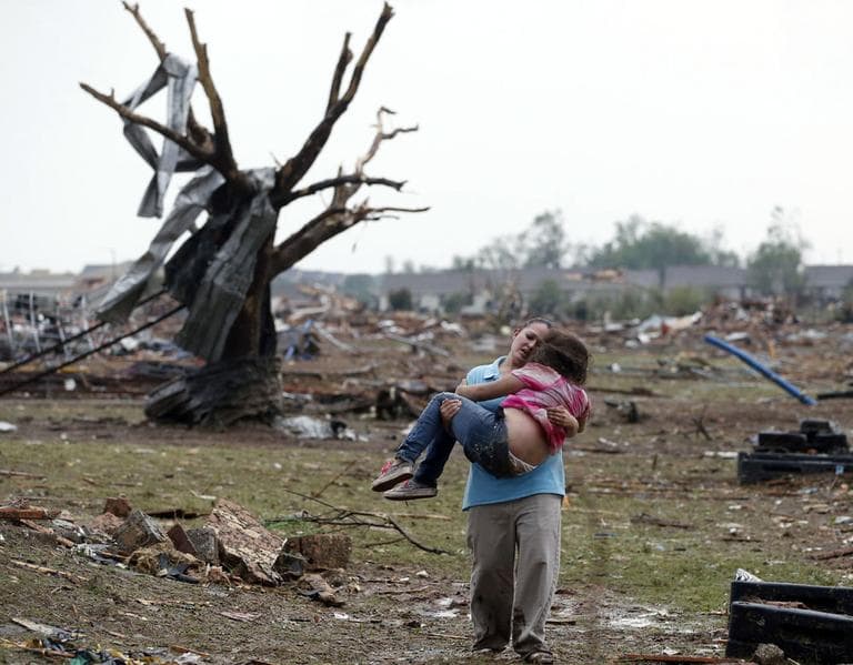 A woman carries a child through a field near the collapsed Plaza Towers Elementary School. (Sue Ogrocki/ AP)